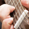 fingers on a fret board, learn to play the guitar